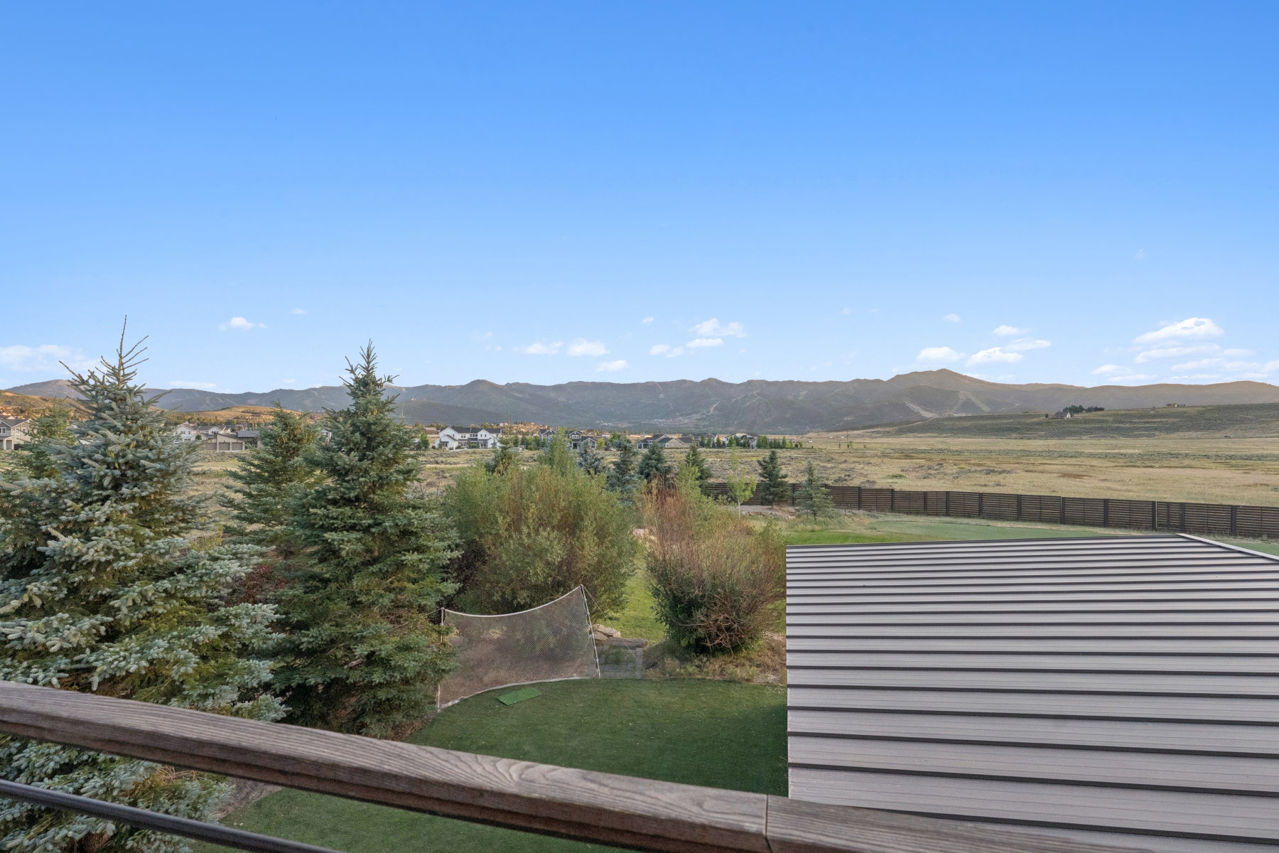 Expansive outdoor area featuring a wood-finish railing, composite decking, and distant mountain scenery