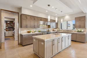 Gourmet kitchen featuring a large central island, light-toned cabinetry, integrated stainless steel appliances, a stone tile backsplash, and recessed lighting
