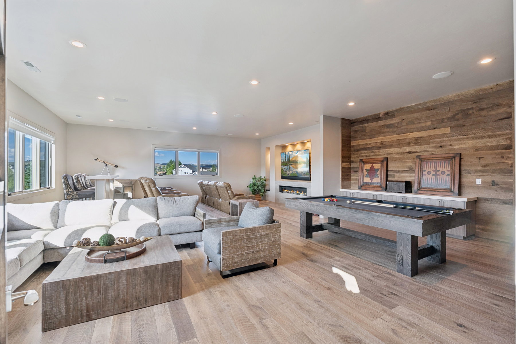 Spacious recreation area featuring wood-finish flooring, a full wood-plank accent wall, and recessed lighting