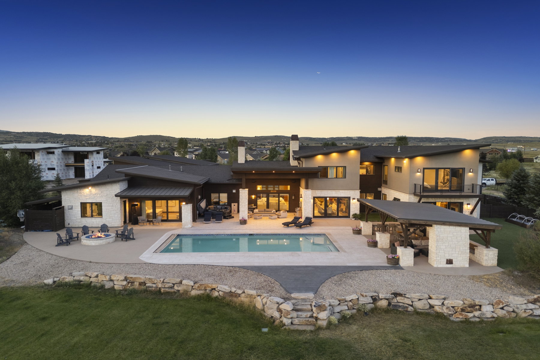 Expansive rear exterior featuring a swimming pool, integrated fire pit area, and a covered outdoor living space