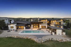 Expansive rear exterior featuring a swimming pool, integrated fire pit area, and a covered outdoor living space