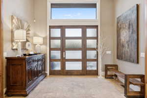 Grand entryway featuring double frosted-glass doors, an overhead transom window, and neutral wall tones