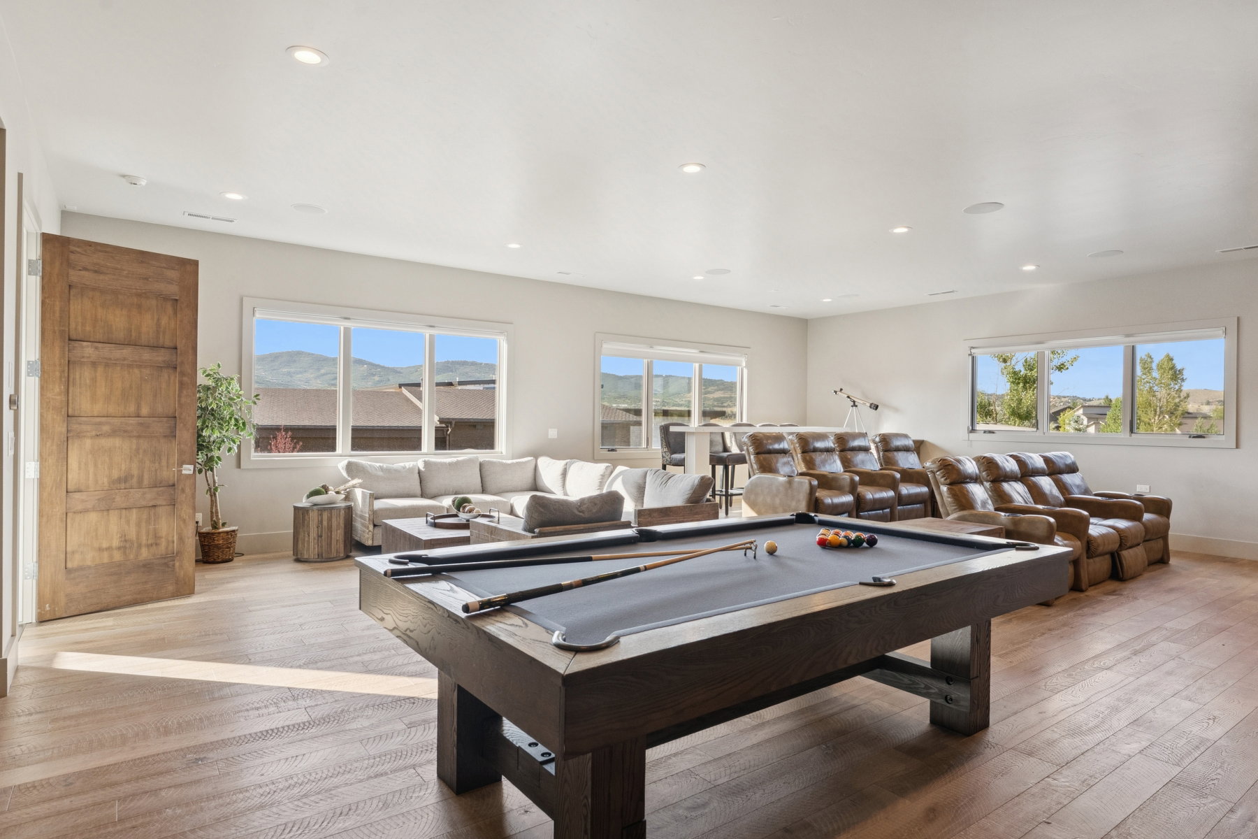 Spacious entertainment room featuring wood-finish flooring, recessed lighting, and multiple large windows