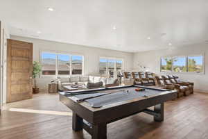 Spacious entertainment room featuring wood-finish flooring, recessed lighting, and multiple large windows