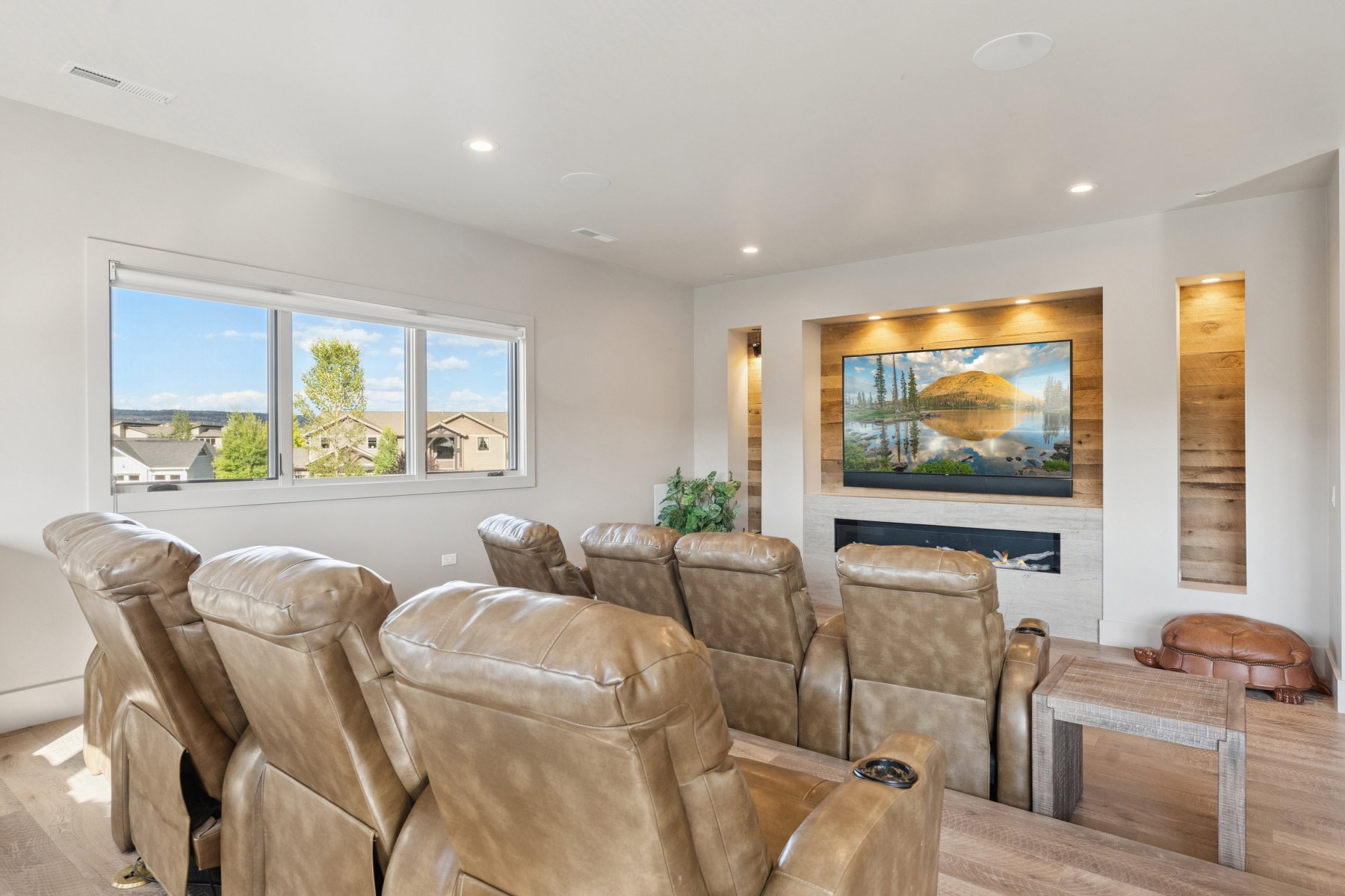 Dedicated entertainment space featuring an integrated media wall with a built-in fireplace and wood-finish accent paneling