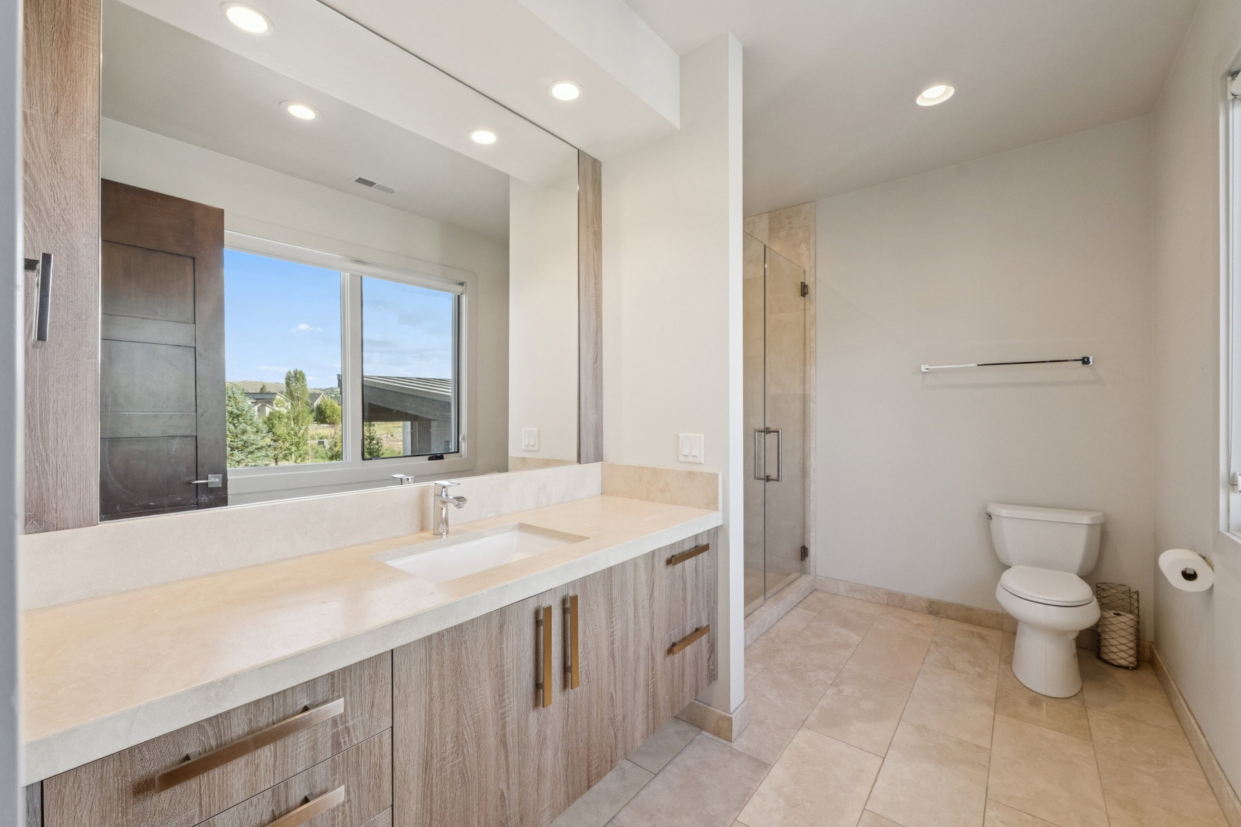Contemporary bathroom featuring a wood-finish double vanity with integrated rectangular sinks and stone-look countertops