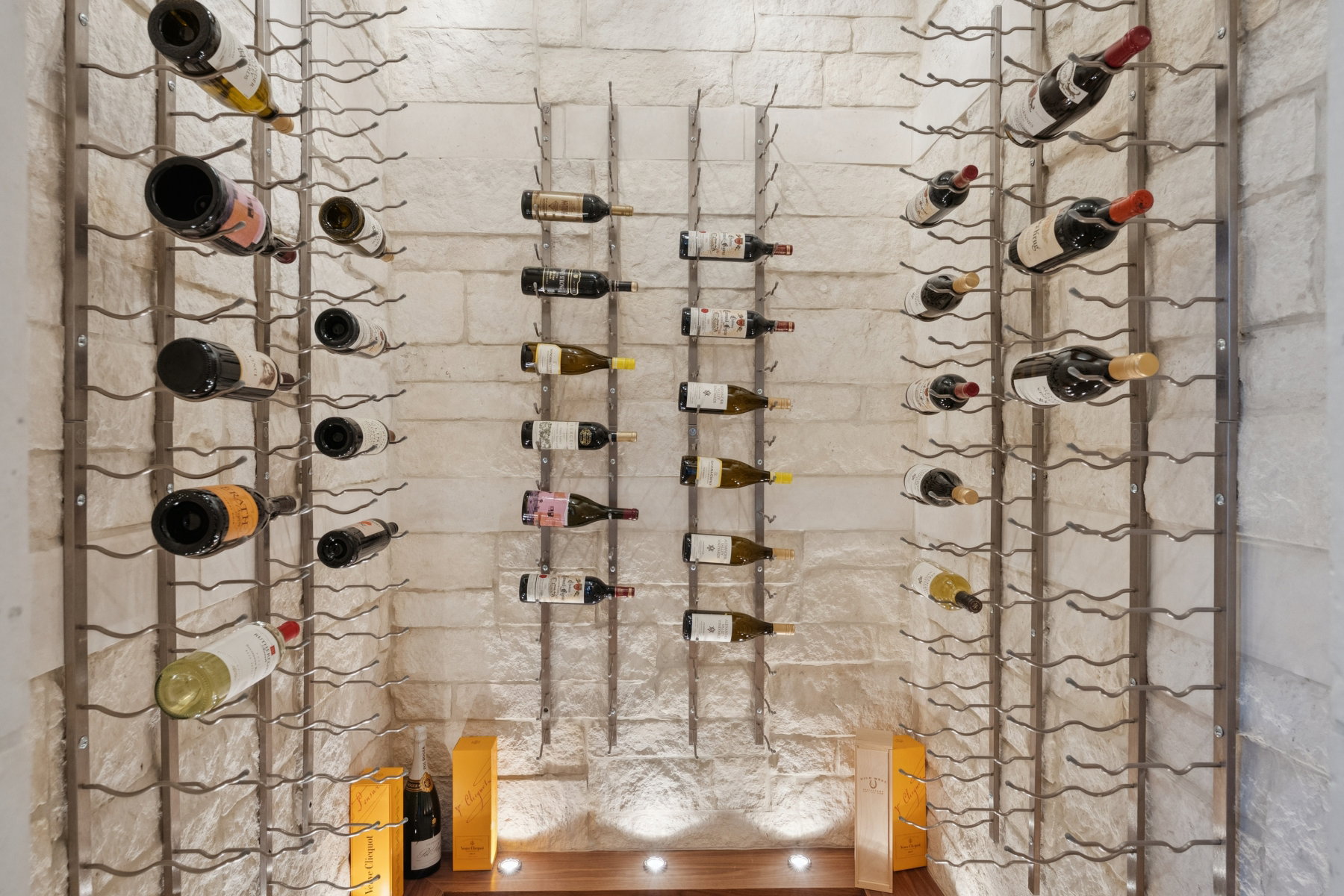 Dedicated wine storage featuring floor-to-ceiling metal racks set against a textured stone-finish wall
