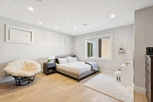 Bedroom featuring wood-finish flooring, recessed lighting, and a window with white trim