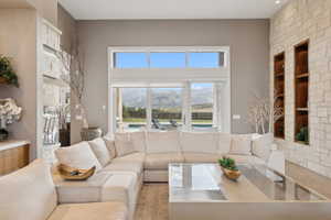 Spacious living area featuring high ceilings, stone accent walls with integrated shelving, and large windows with transom panels