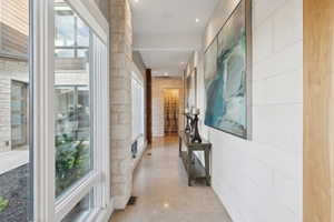Hallway featuring expansive windows, recessed lighting, stone veneer wall accents, wood-finish flooring, and a white paneled wall