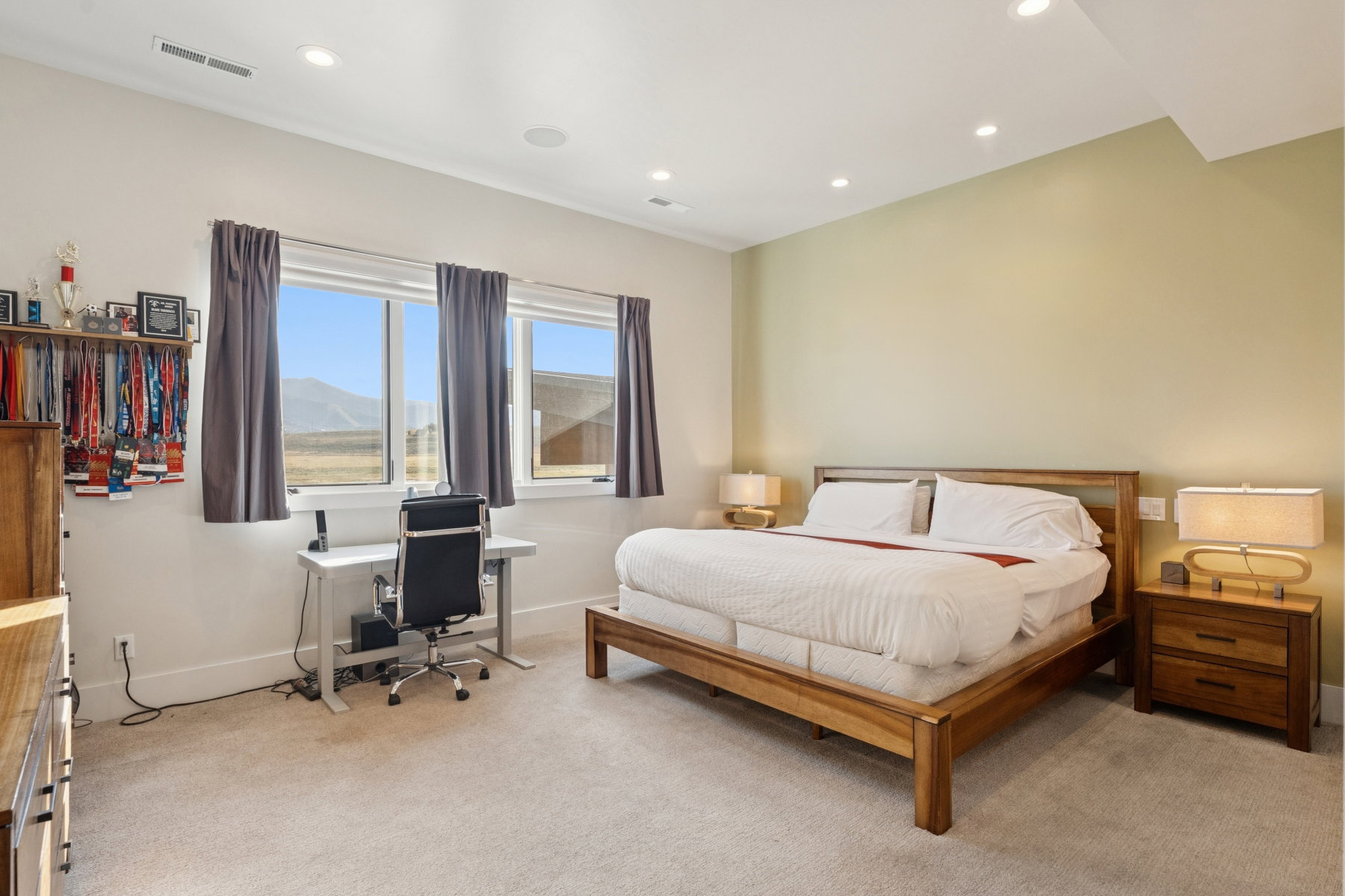 Bedroom featuring a large window, recessed ceiling lighting, light-colored carpeting, a wall-mounted speaker, and a wall-mounted vent