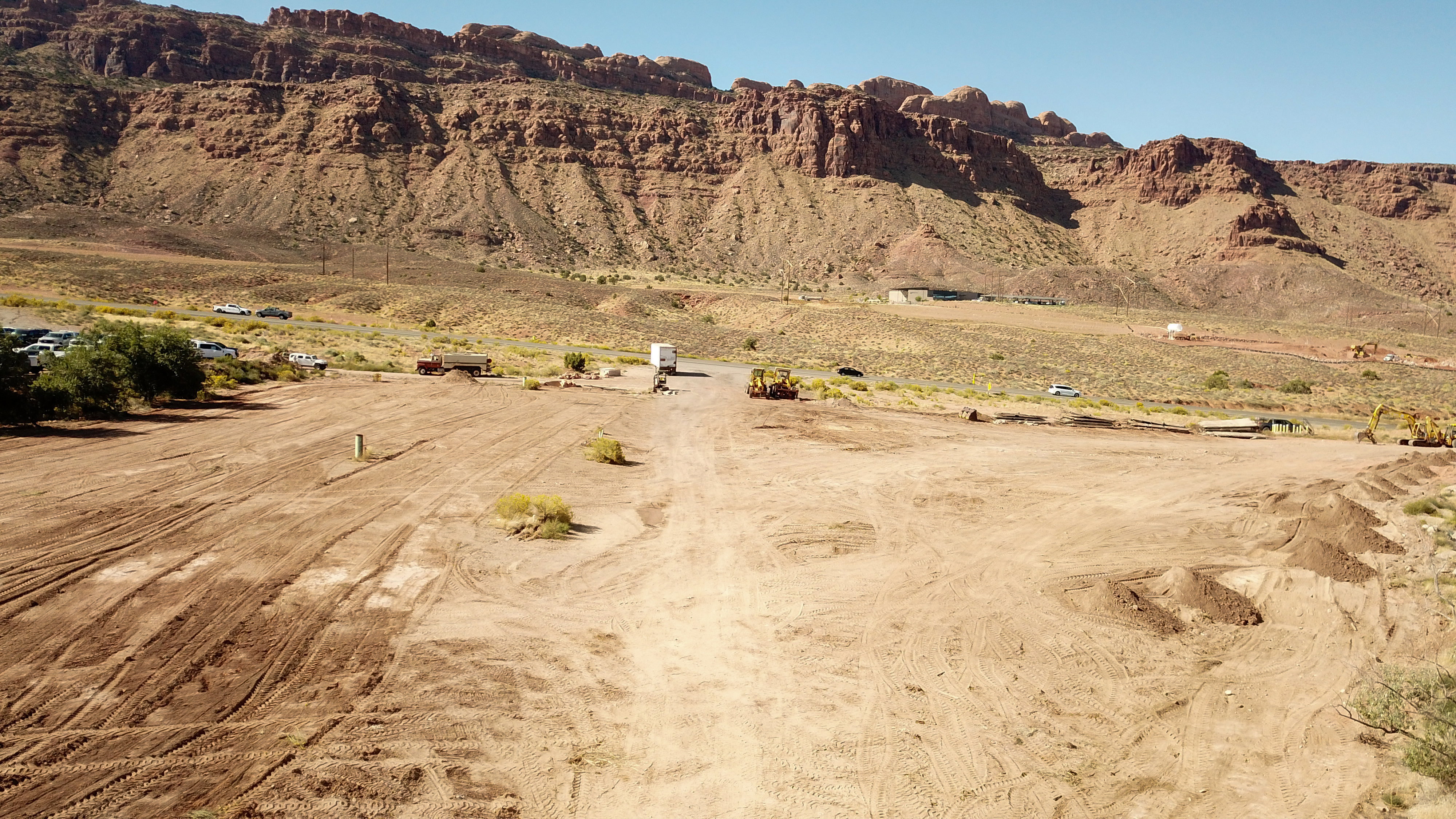Expansive cleared land featuring visible earthworks and a distant mountainous backdrop