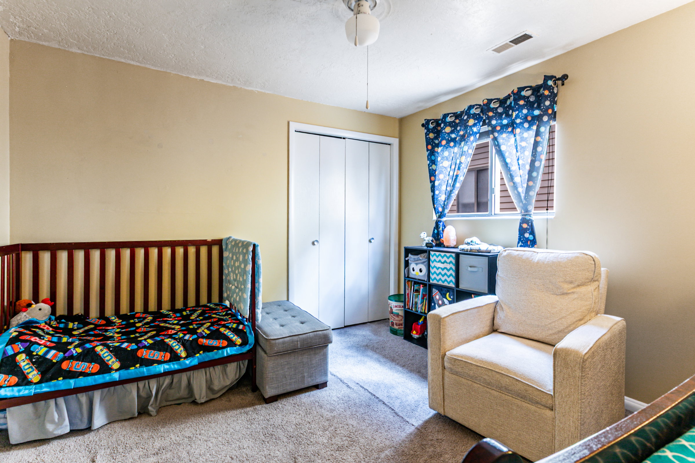 Carpeted room featuring neutral wall tones, a window with horizontal blinds, and a ceiling fan with integrated lighting