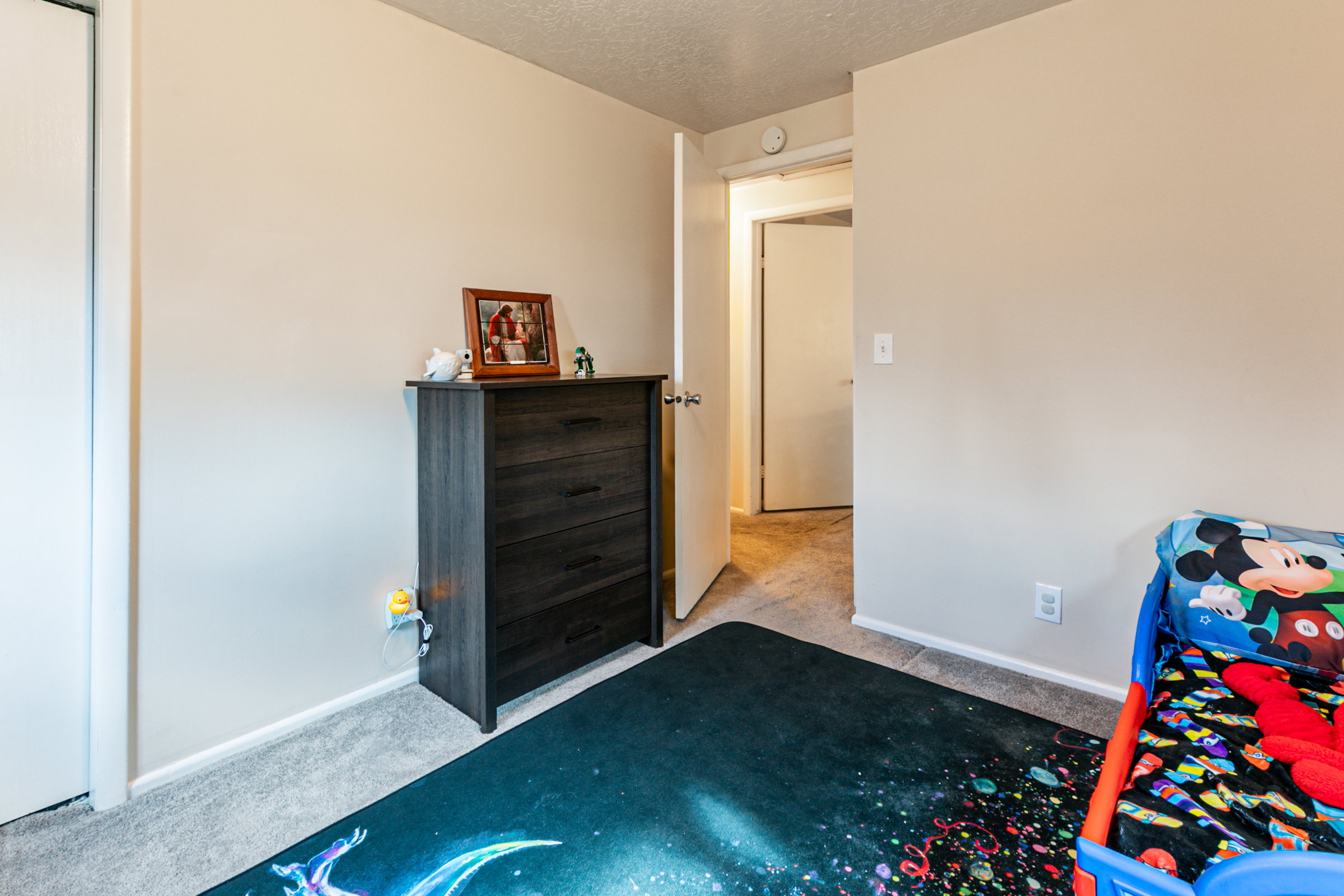 Neutral-toned wall space with white baseboards and gray carpet flooring