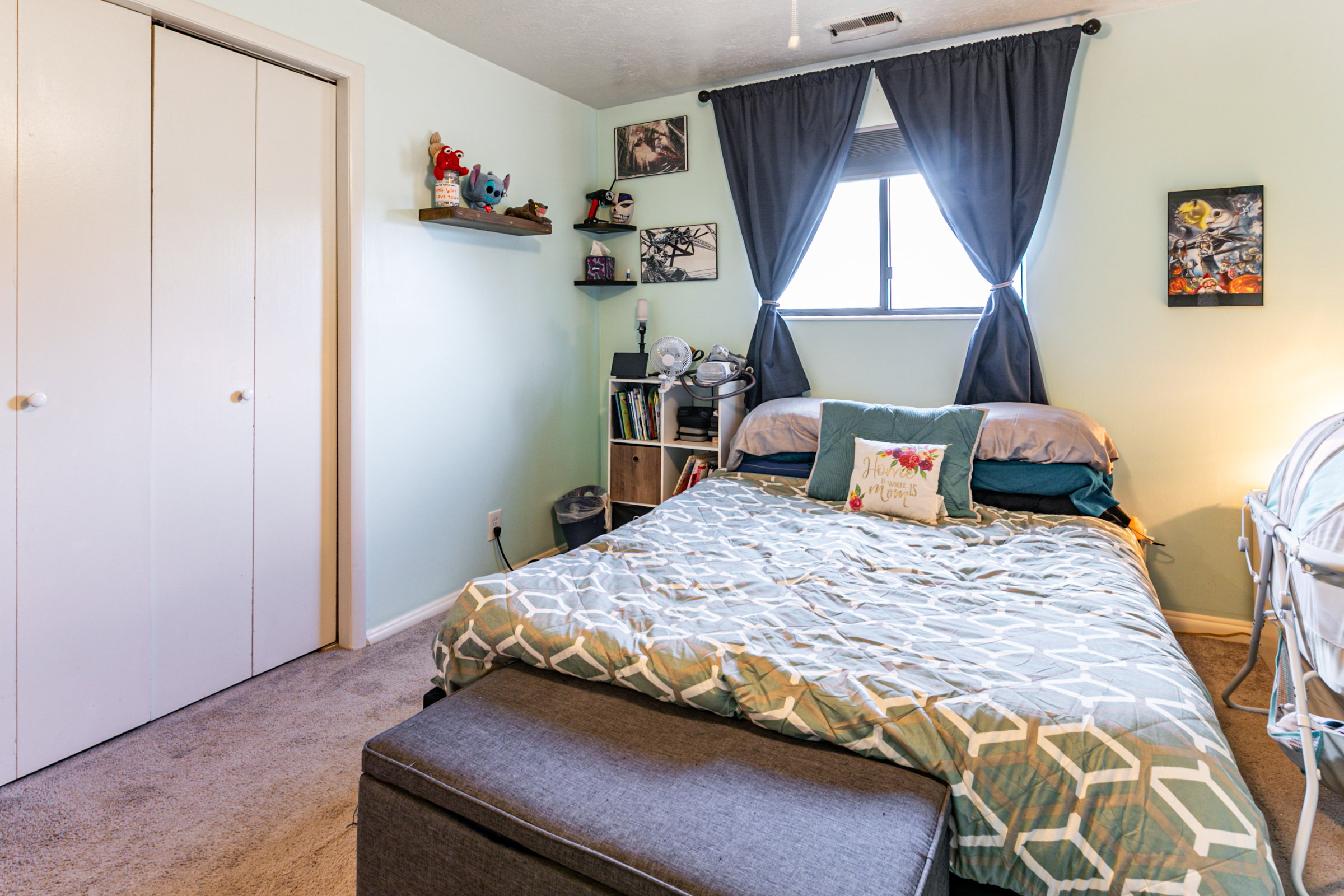 Bedroom featuring light green walls, a window with dark curtains, and light-colored carpet flooring
