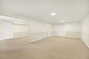 Spacious carpeted room featuring recessed lighting, a white paneled door, and bi-fold louvered closet doors