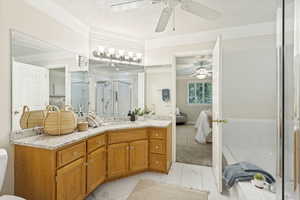 Bathroom featuring a dual vanity with light wood cabinetry, a light speckled countertop, and large wall-mounted mirrors