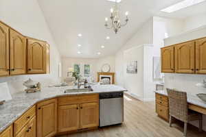 Kitchen featuring wood cabinetry, light-toned countertops, an undermount sink, and a built-in stainless steel dishwasher