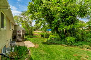 Expansive green lawn with mature trees and a multi-level wood deck