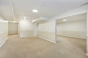 Spacious carpeted room featuring recessed lighting, a neutral color palette, and wainscoting with a textured pattern