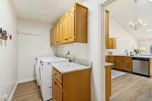 Dedicated laundry area featuring wood-finish flooring, light-toned walls, and overhead cabinetry