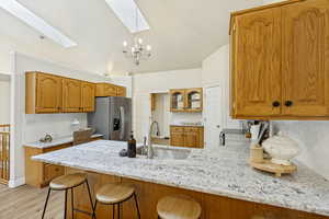 Kitchen featuring a large island with a light-colored speckled countertop, undermount sink, and seating for three