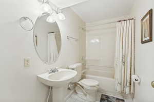 Pedestal sink with chrome faucet, an oval mirror, and a three-light vanity fixture