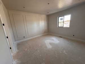 Room featuring a decorative accent wall with panel molding, recessed ceiling lighting, a single window, and a door with dark hardware