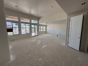 Spacious interior featuring multiple large windows, a sliding glass door, recessed lighting, and a white interior door with matte black hardware