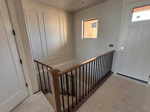 Entryway featuring a wood-finish staircase with wrought iron balusters, panel molding accent wall, and a solid panel door with upper glass paneling