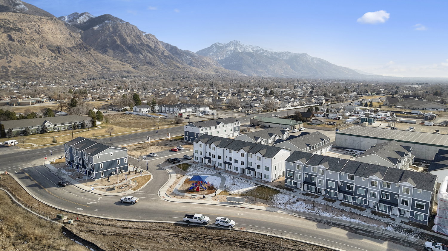 Community featuring newly constructed townhomes, mountain scenery, and a central playground area