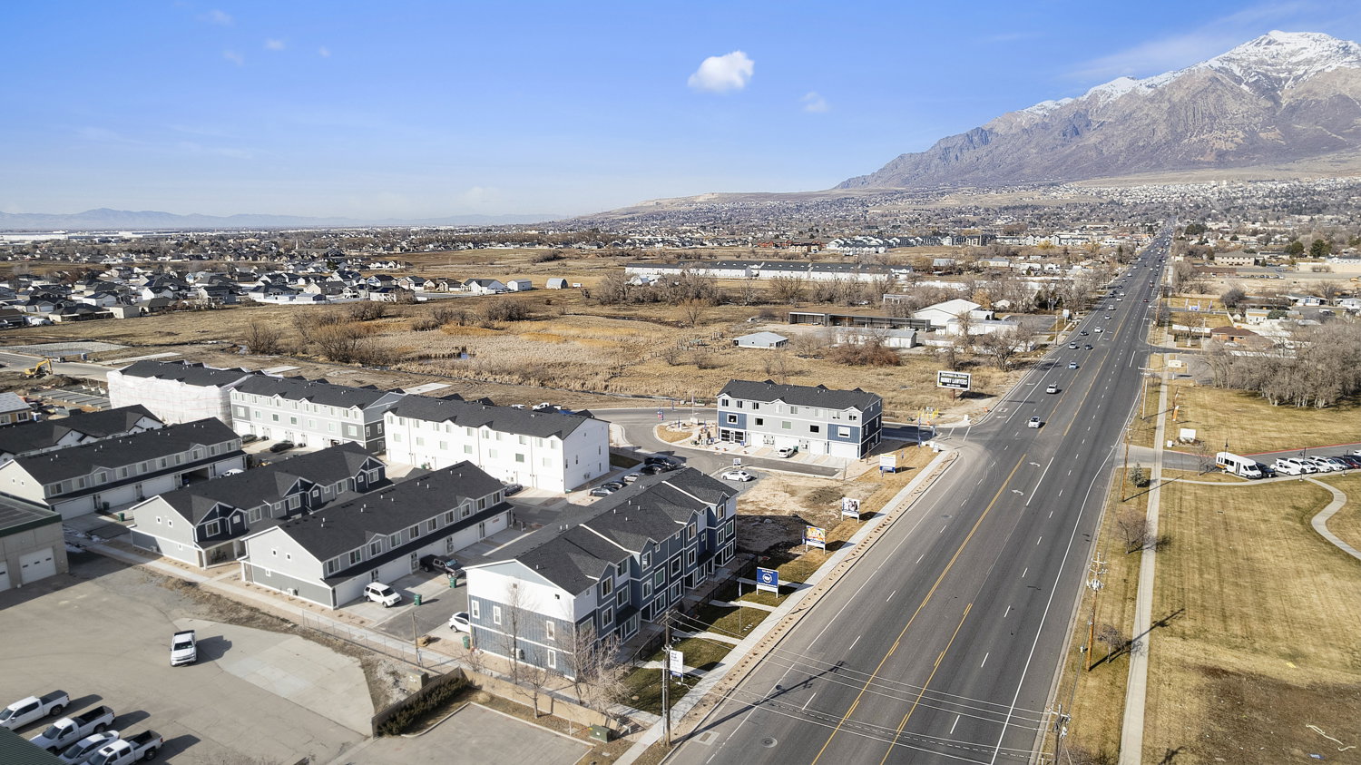 Aerial perspective showcasing multiple modern residential buildings with dark roofs and light-colored siding