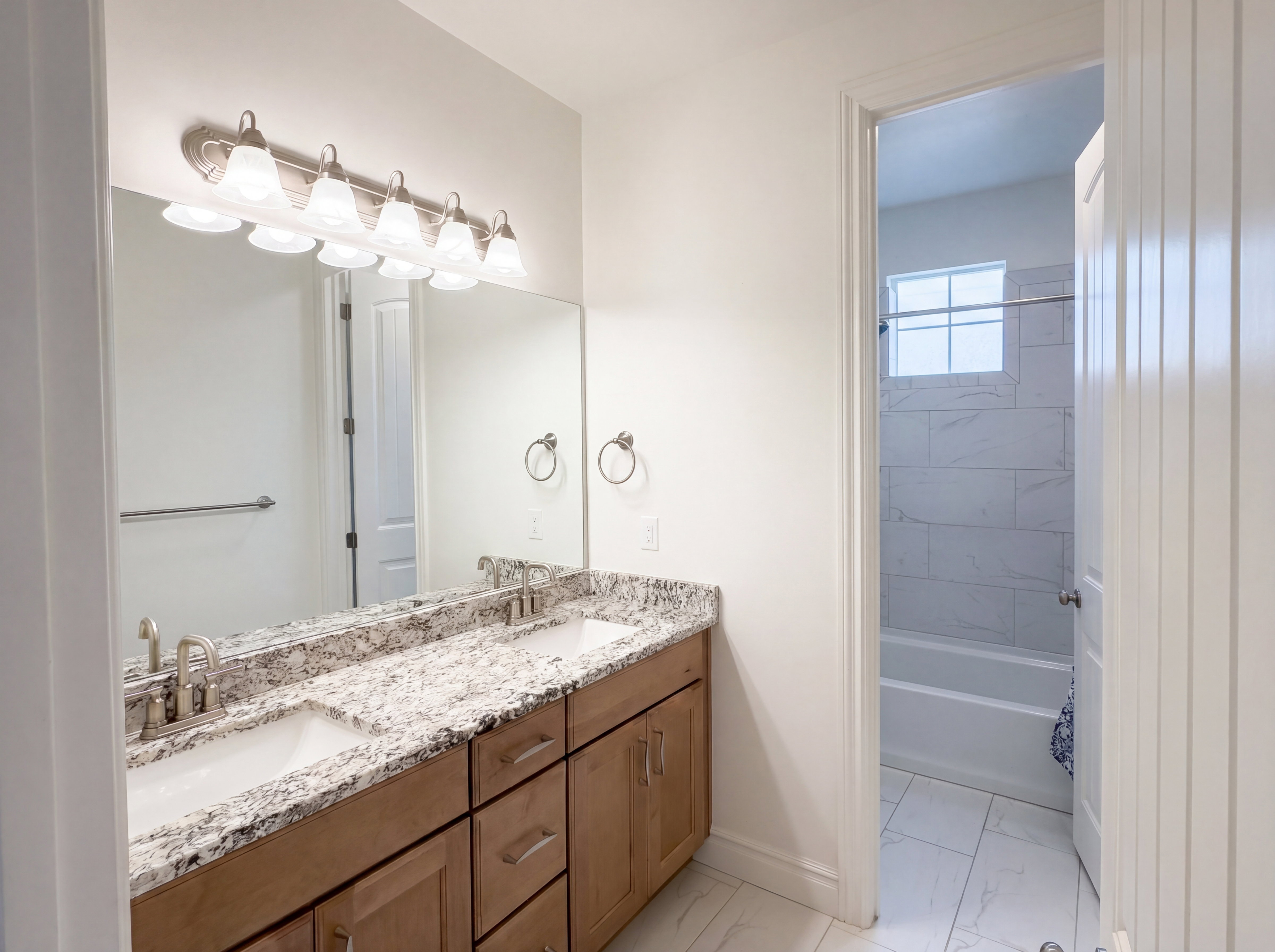 Bathroom vanity featuring dual undermount sinks set in a stone countertop with wood-finish cabinetry