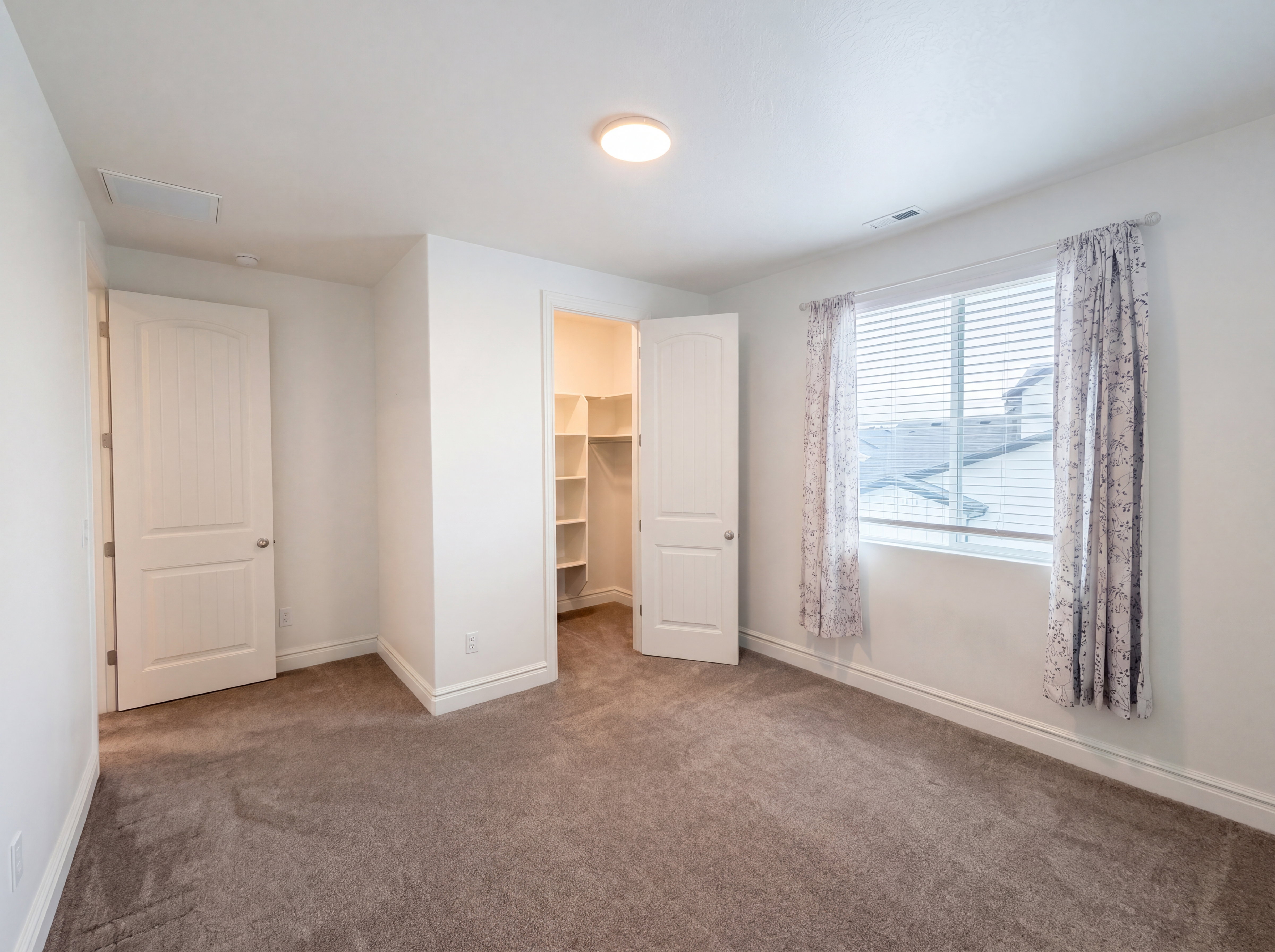 Carpeted room featuring a window with blinds, white trim, a flush mount ceiling light, and a built-in closet with shelving