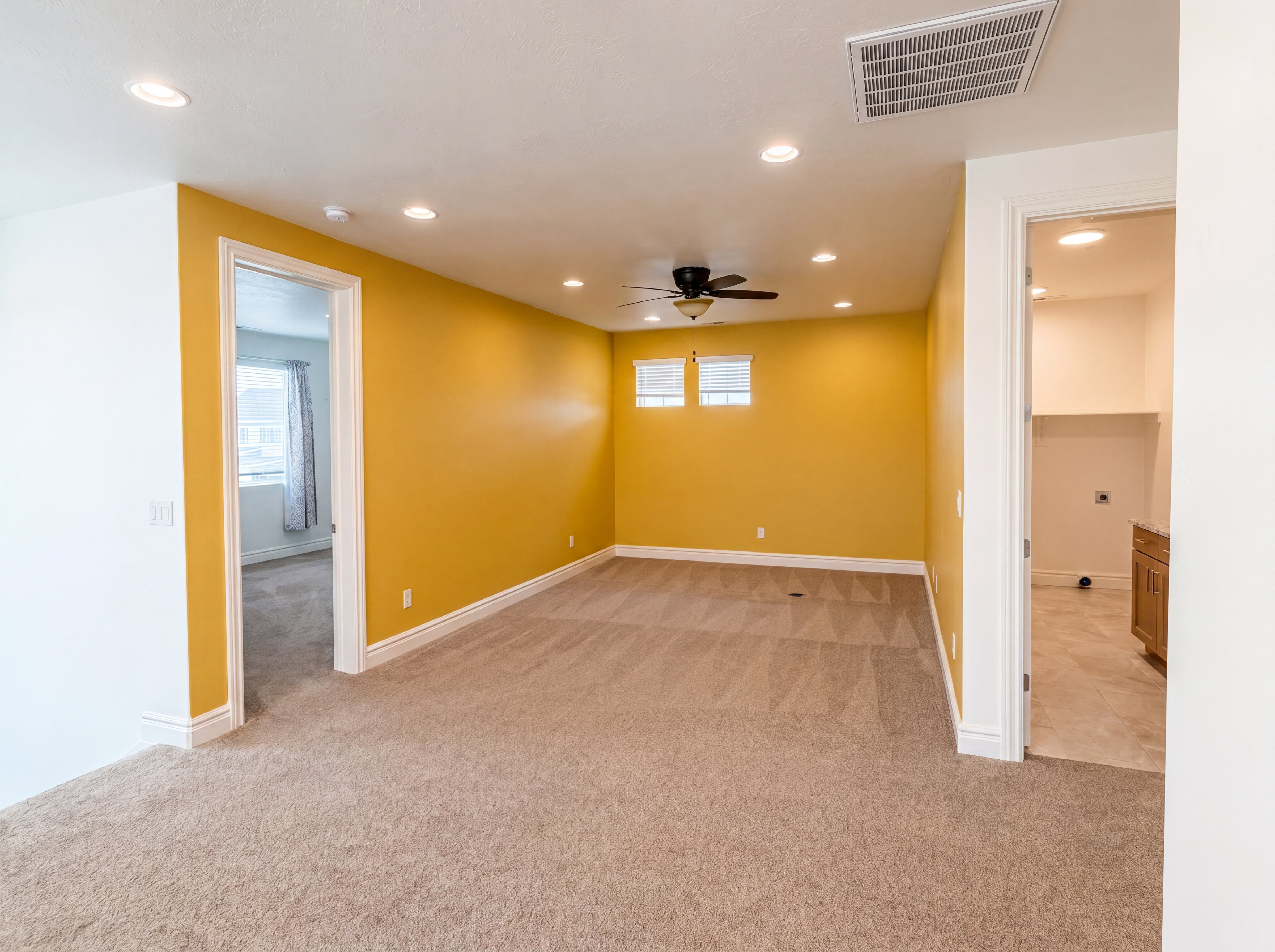 Spacious carpeted room featuring recessed lighting, a ceiling fan, and two windows