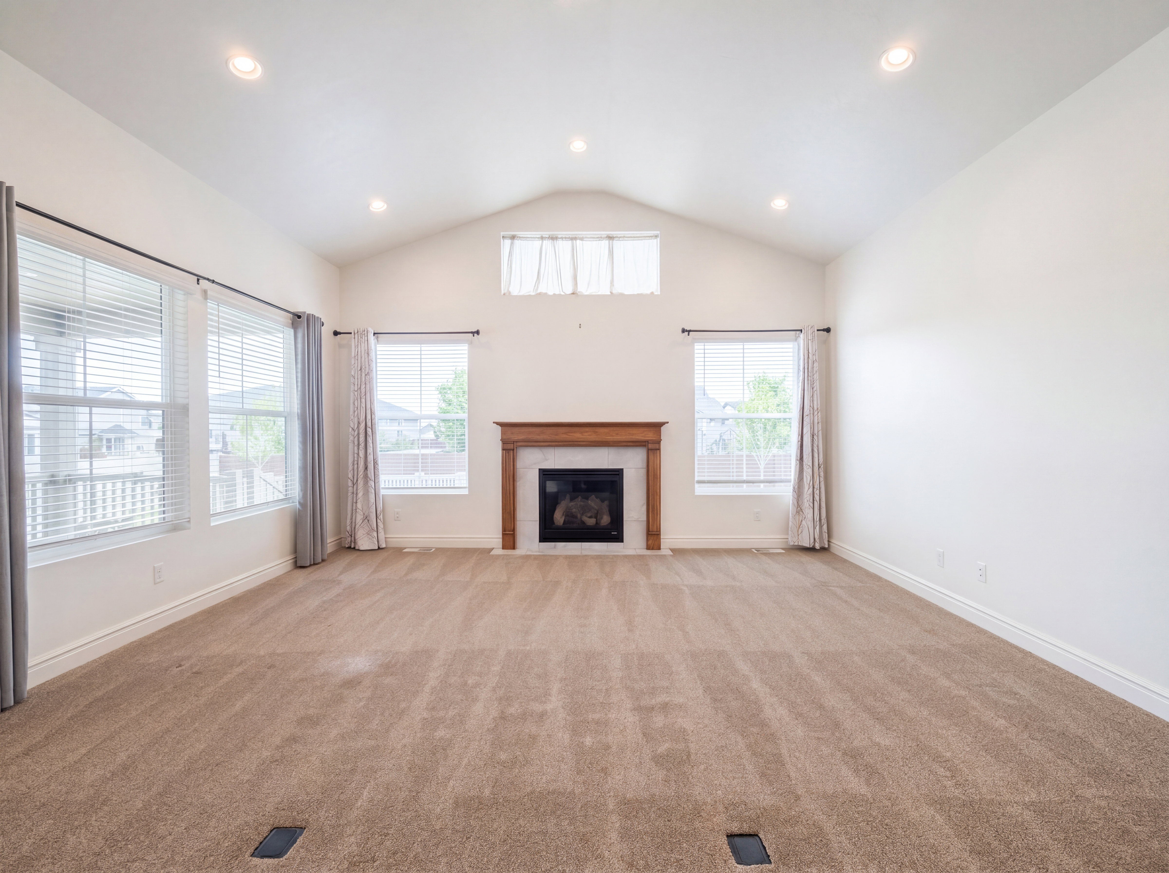 Spacious living area featuring a vaulted ceiling with recessed lighting