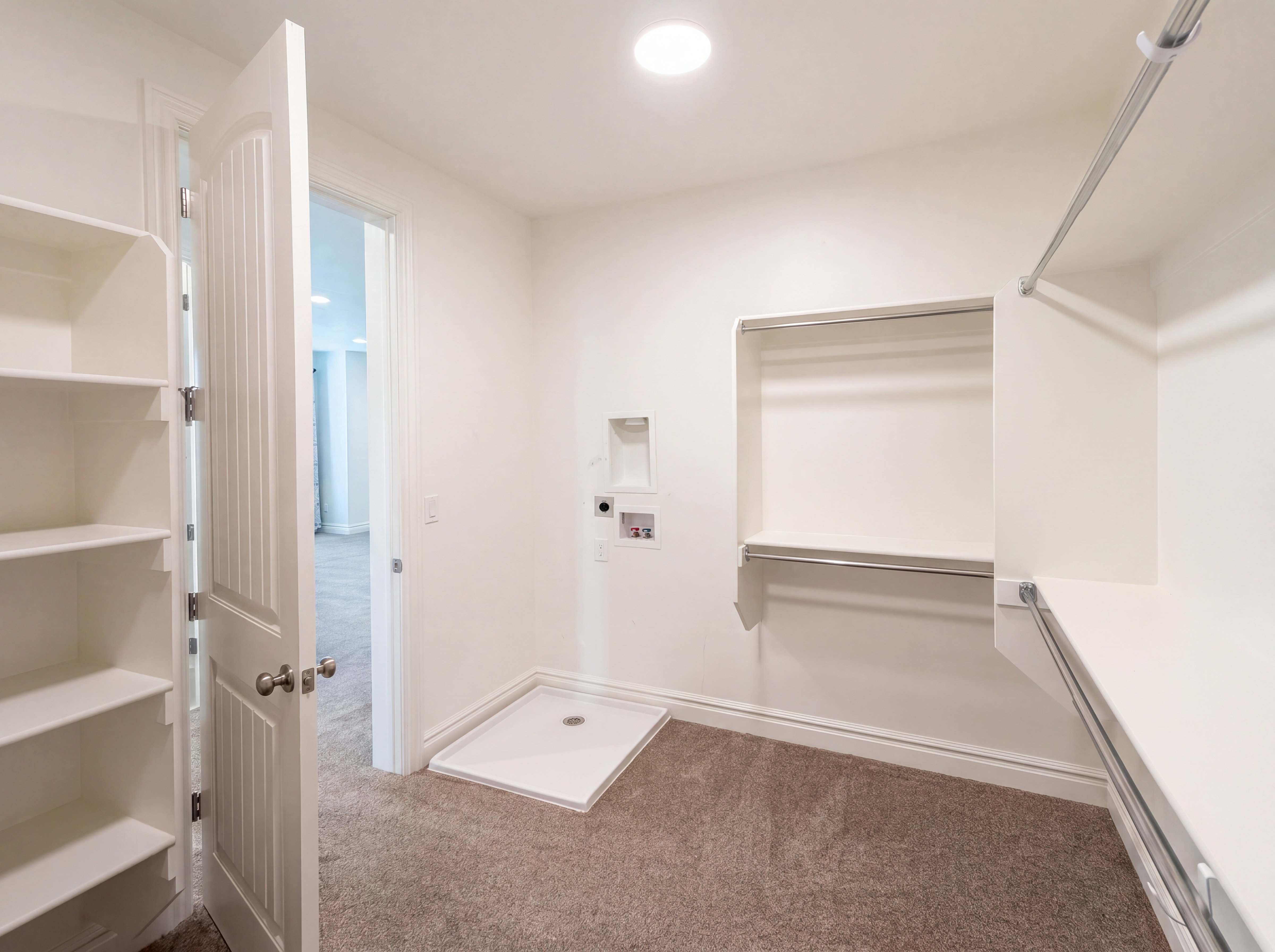 Walk-in closet featuring extensive built-in shelving, multiple hanging rods, and a laundry hookup area with a washer pan