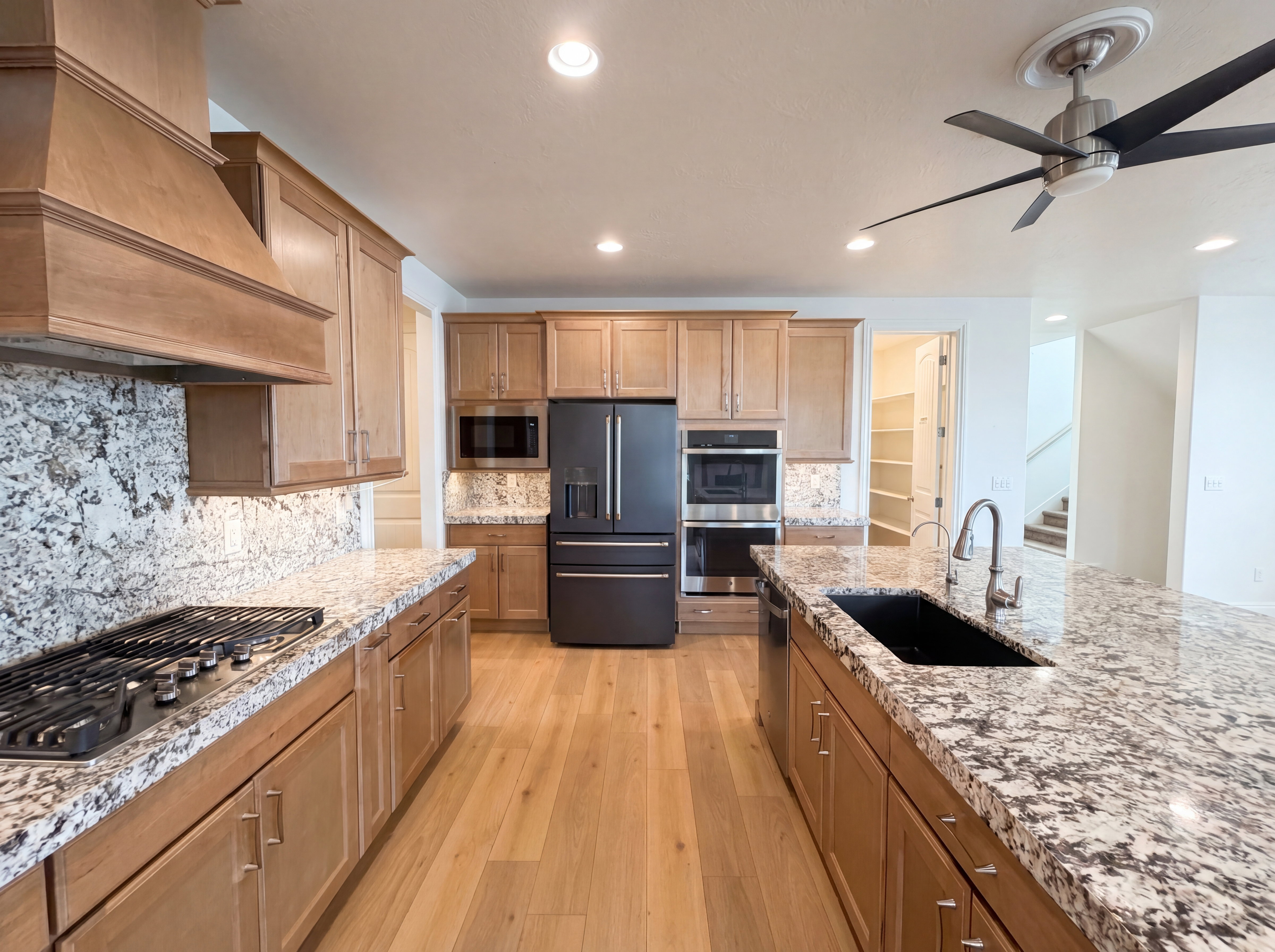 Modern kitchen featuring light wood cabinetry, stone countertops, and wood-finish flooring