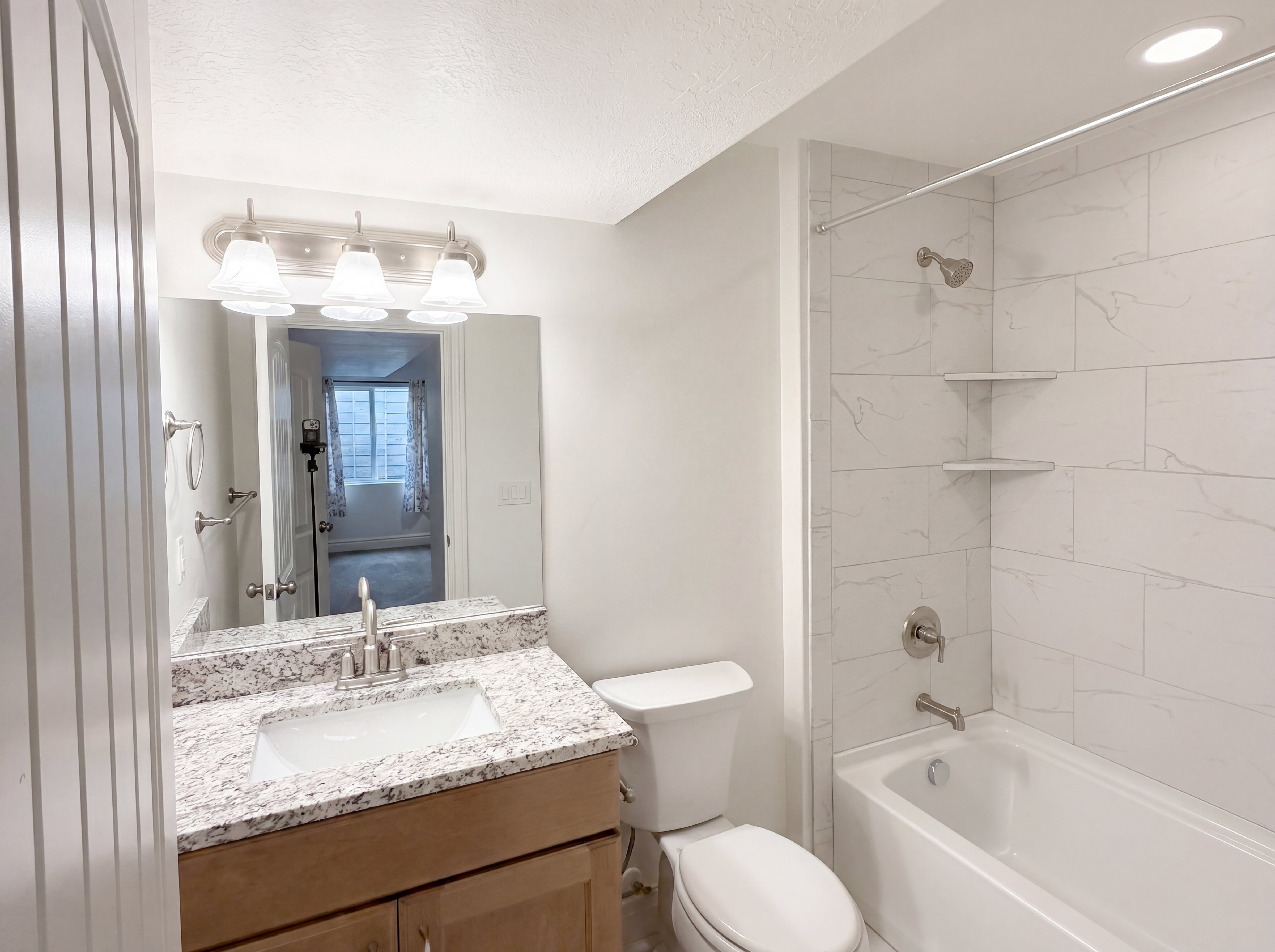 Bathroom featuring a vanity with a granite-finish countertop, undermount sink, and brushed nickel faucet