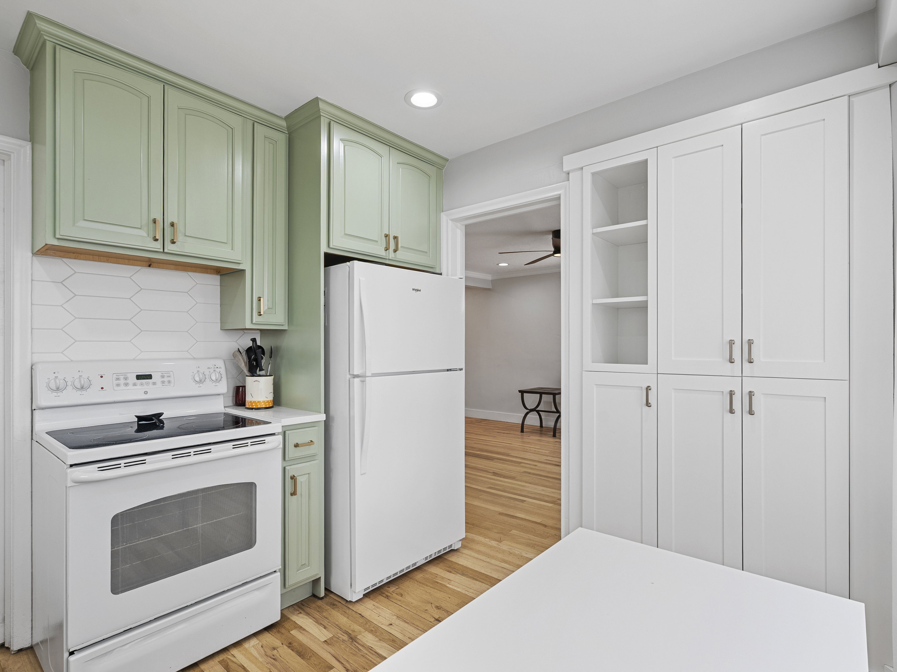 Kitchen featuring two-tone cabinetry with light green upper cabinets and white lower storage, a white electric range, and a white refrigerator
