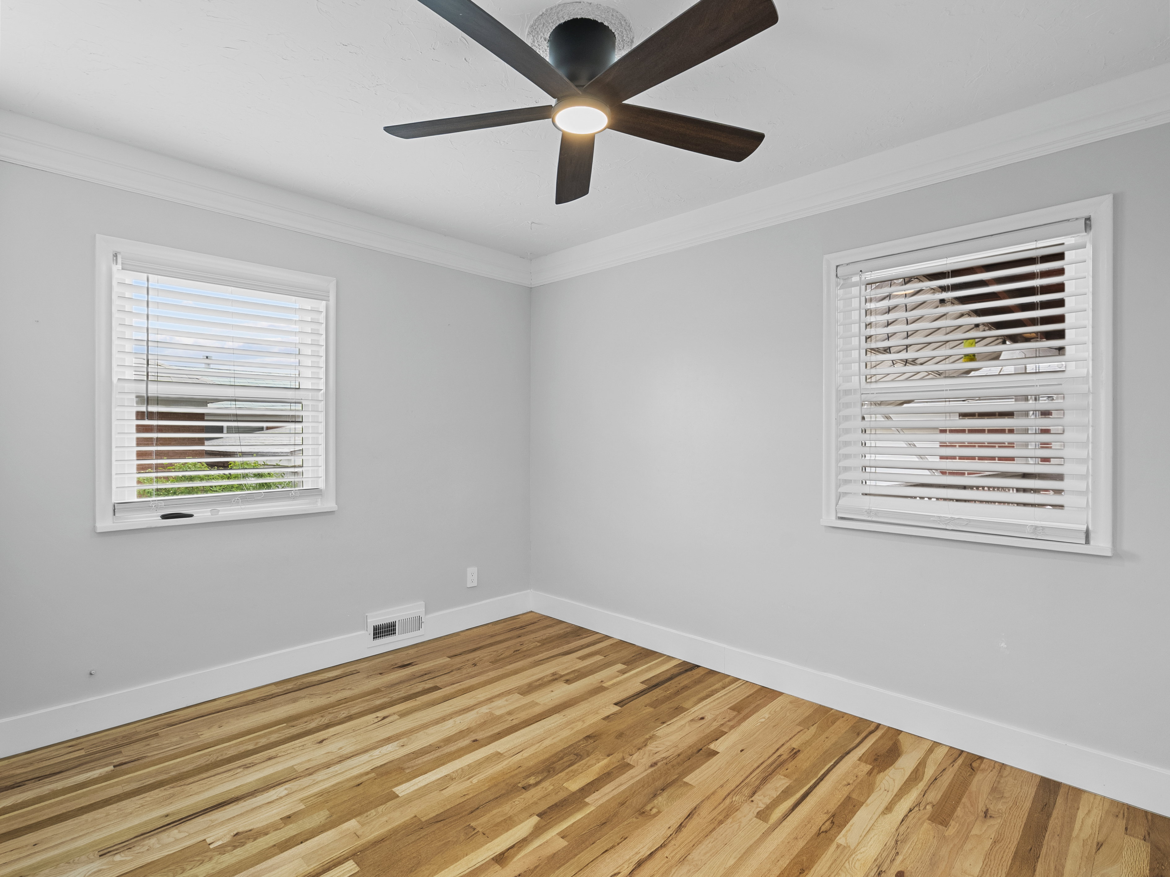 Hardwood flooring room with two windows featuring white blinds