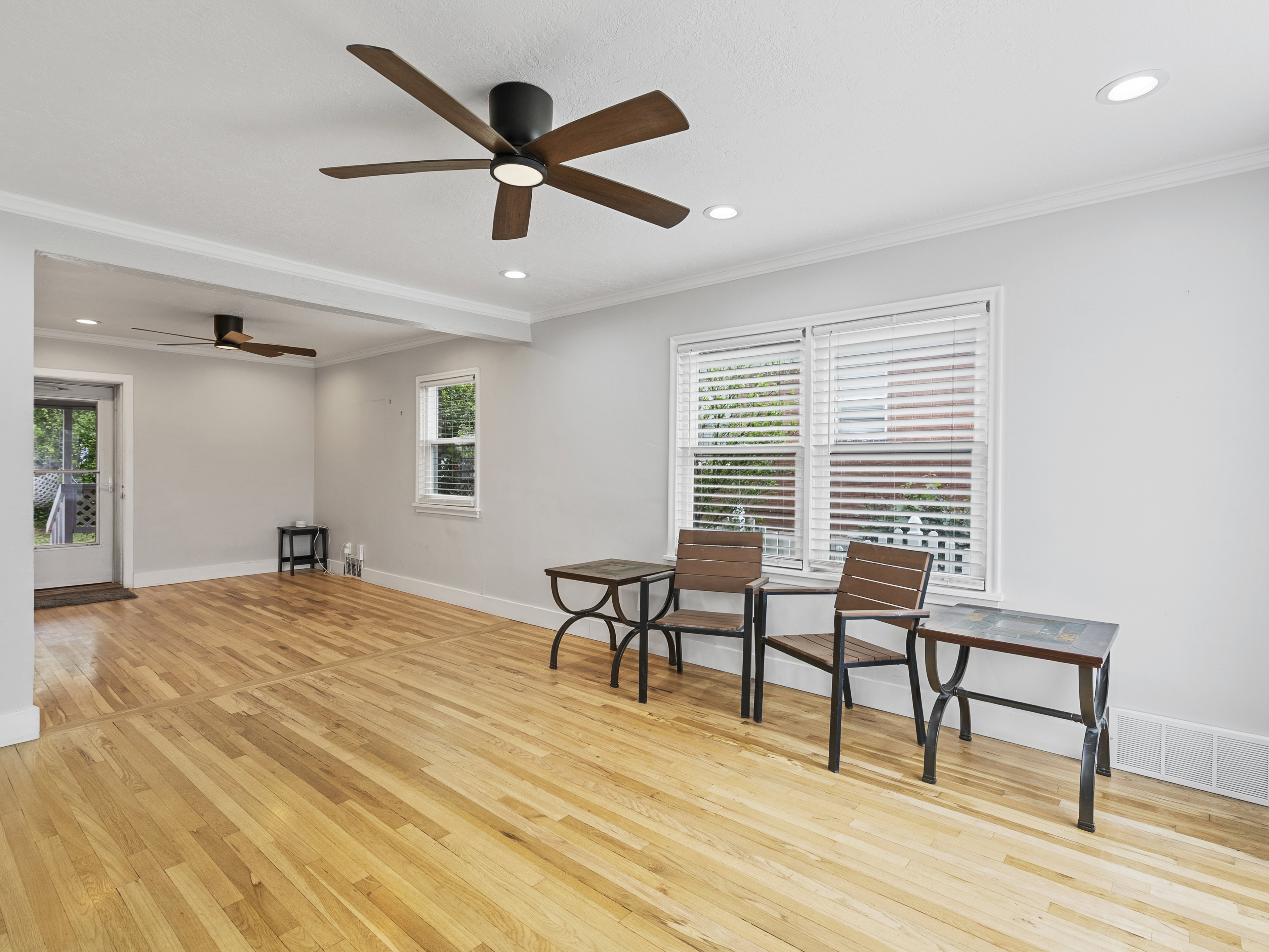 Bright open-concept living area featuring light wood-finish flooring, recessed lighting, and two ceiling fans with integrated lighting