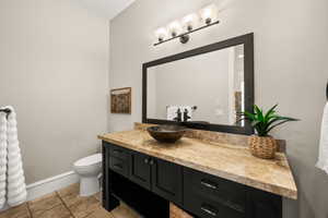 Powder room featuring a dark wood vanity with a vessel sink, a light-toned stone countertop, and a large framed mirror