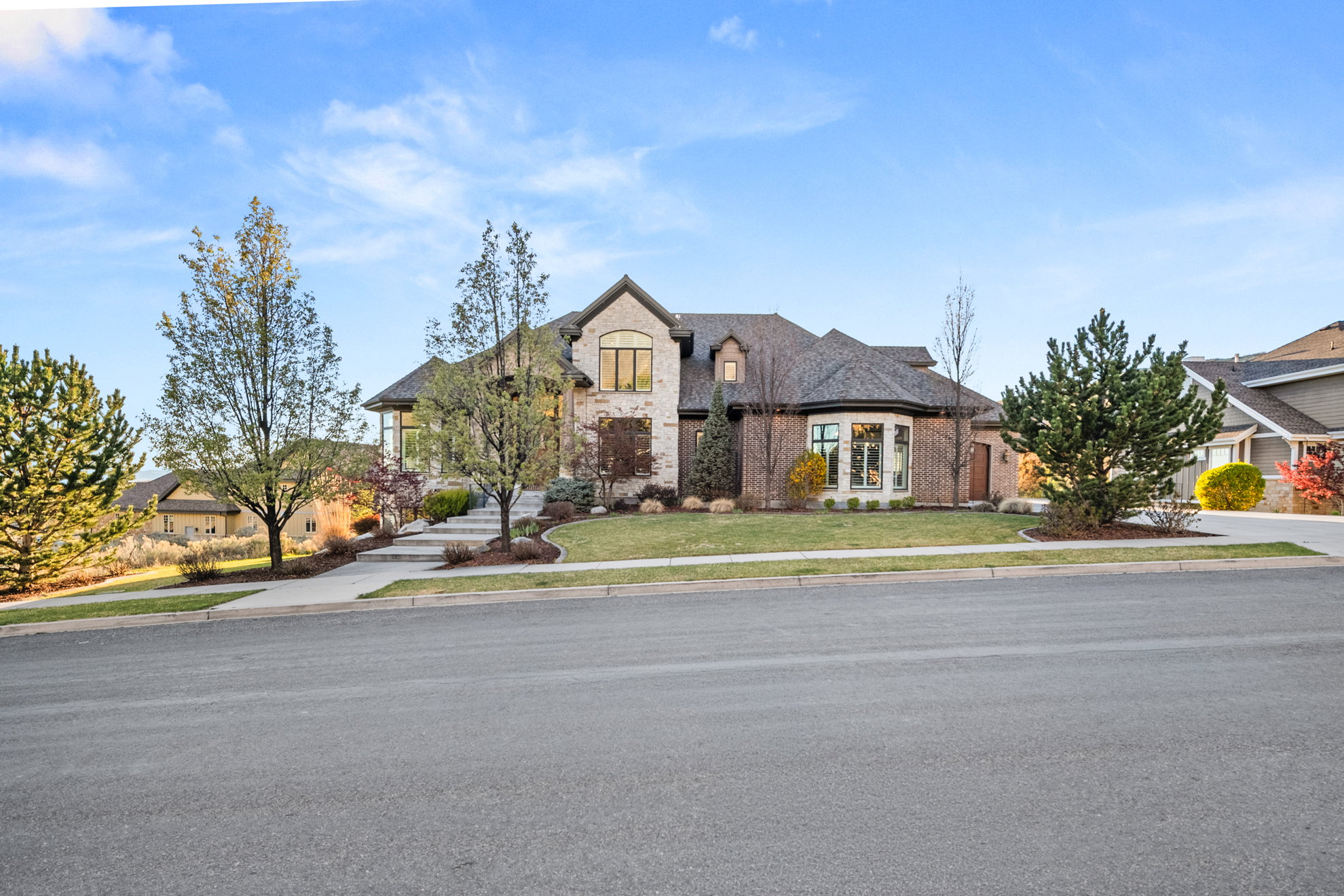 Stone and brick exterior featuring a multi-gabled roofline, a curved bay window, and extensive landscaping