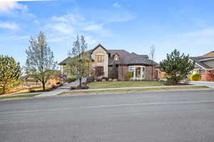 Stone and brick exterior featuring a multi-gabled roofline, a curved bay window, and extensive landscaping
