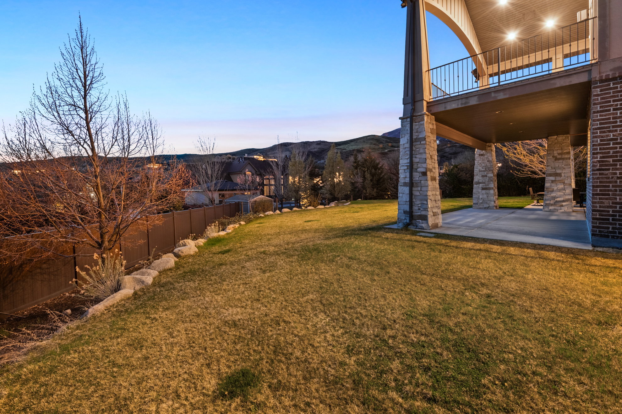 Spacious rear yard with a sloped lawn and mature landscaping