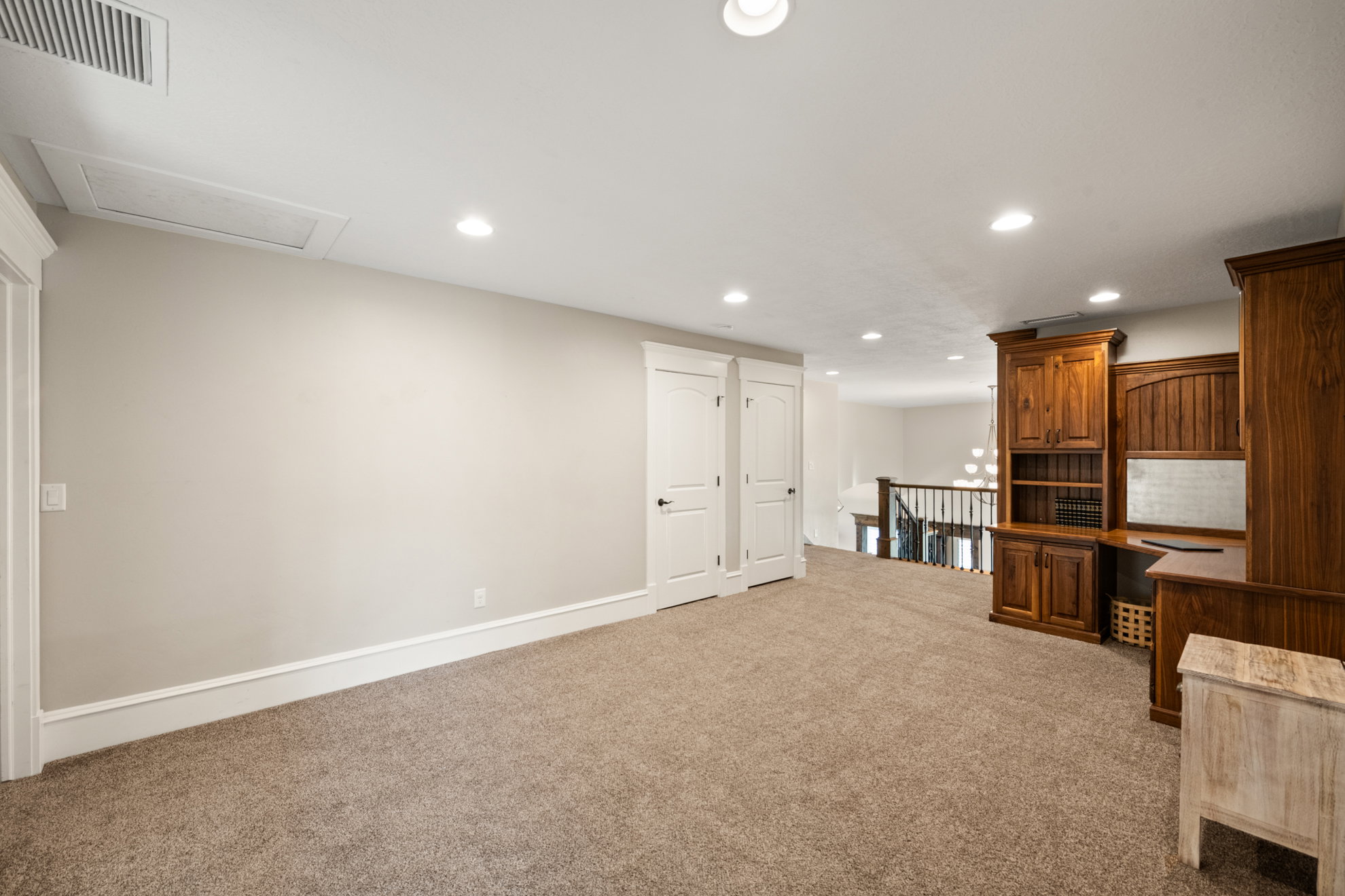 Open loft space featuring built-in wood cabinetry, recessed lighting, and soft carpet flooring