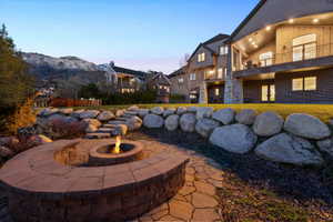 Expansive backyard featuring a built-in stone fire pit with curved seating, flagstone pathway, and rock retaining walls