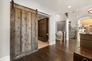 Wide plank wood-finish flooring throughout the entryway, featuring a prominent barn door with black hardware