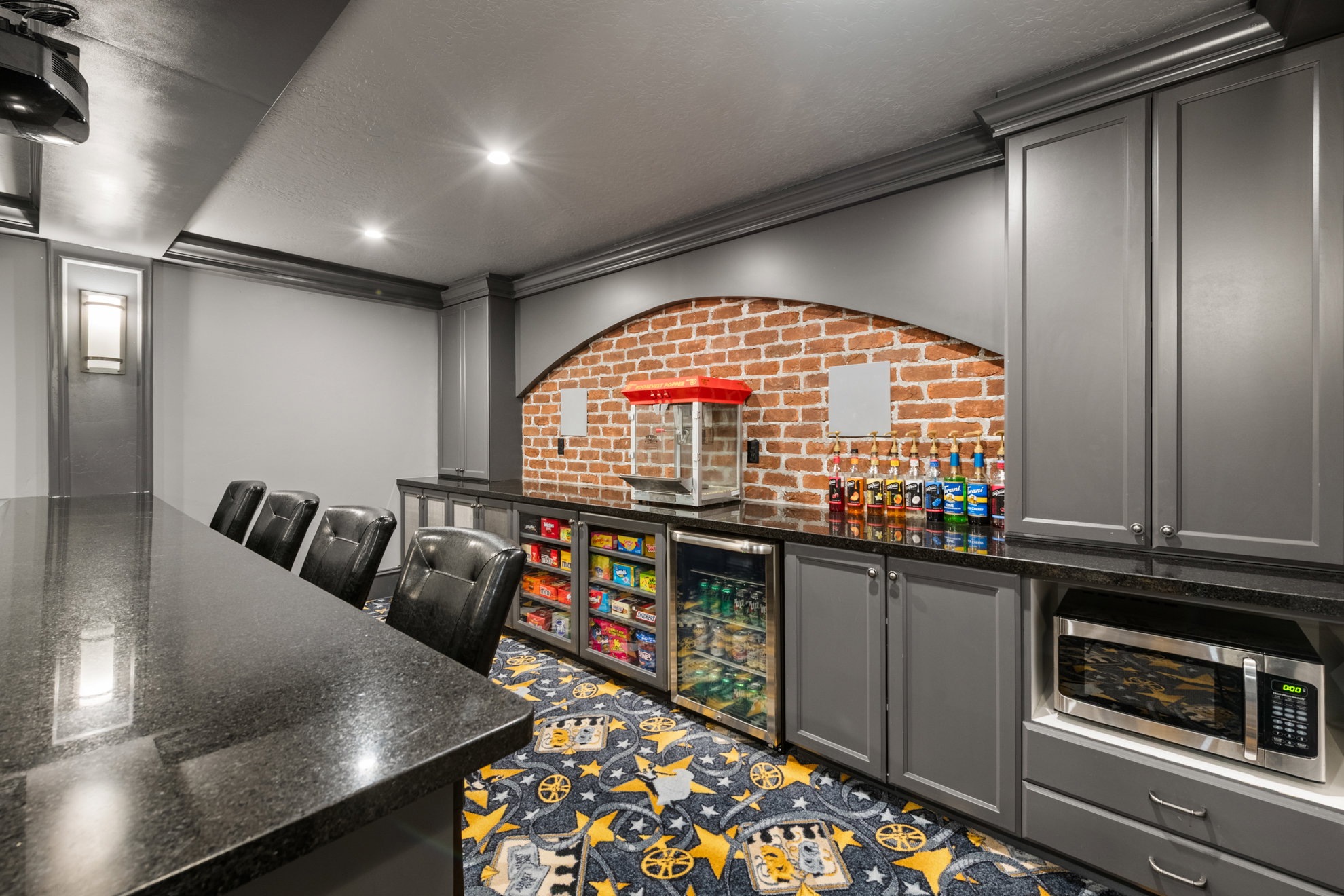 Entertainment area featuring a long black countertop, recessed lighting, and a brick-finish accent wall